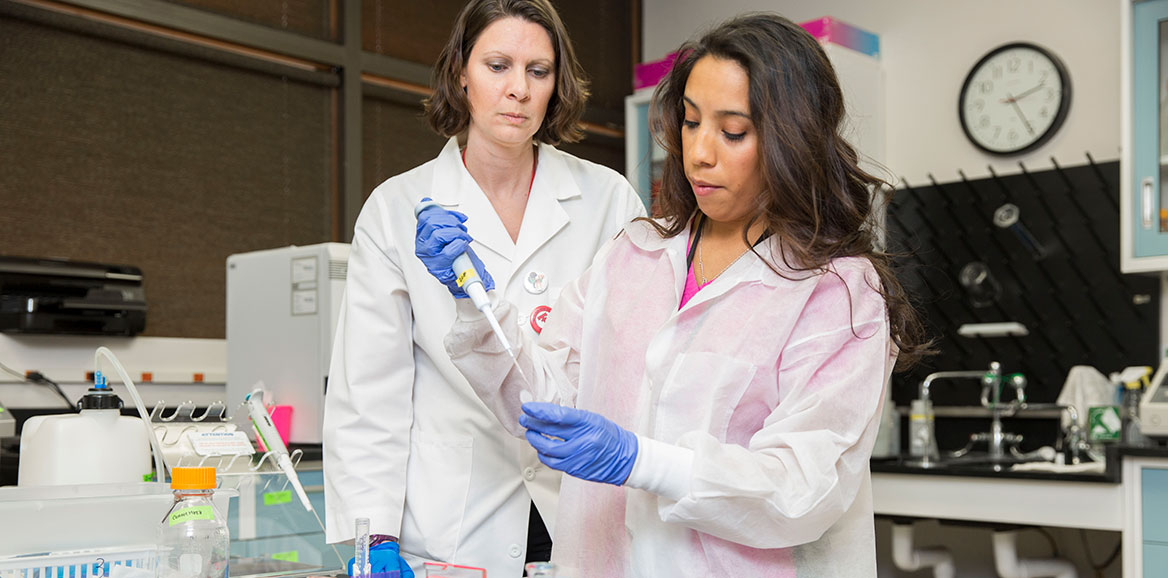 A student performs a lab task under the supervision of an instructor