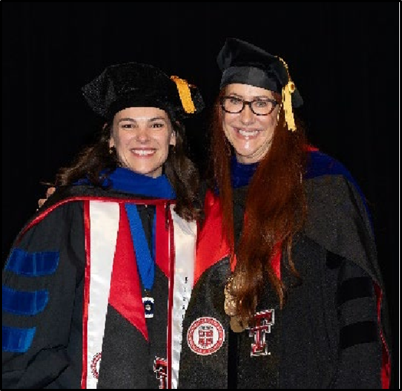 A graduate in a doctoral robe receives a ceremonial hood from a faculty member during commencement.