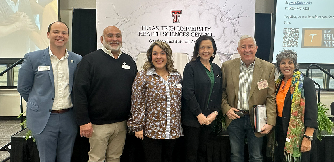 Group of six Garrison Institute on Aging team standing together at a conference infront of a TTUHSC GIA backdrop