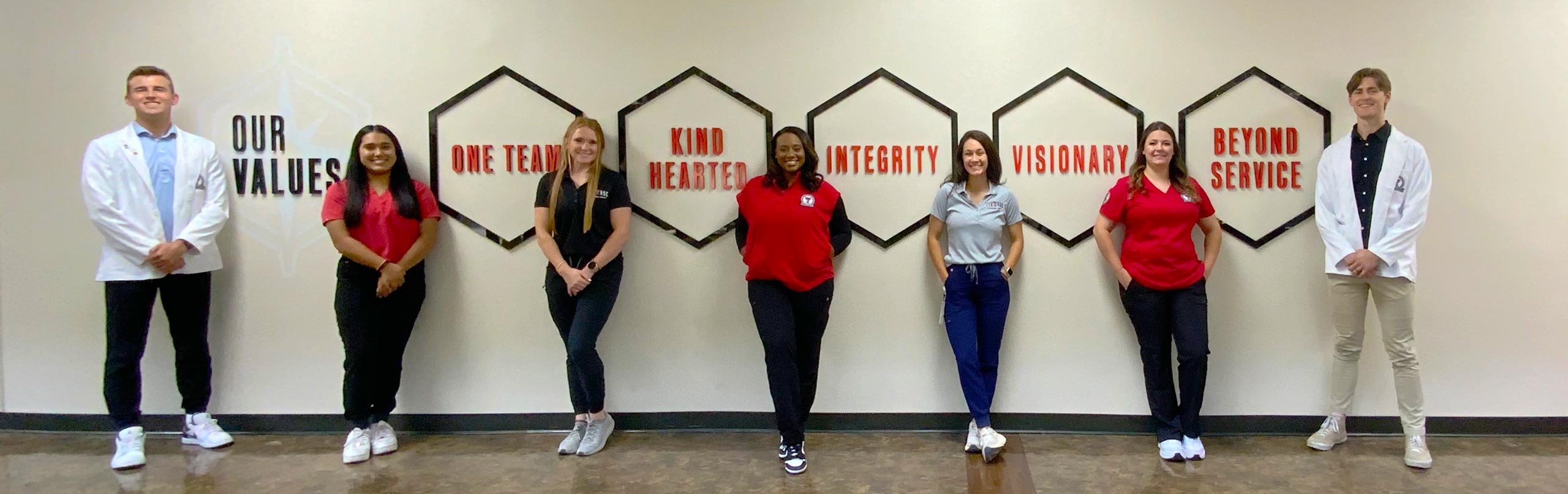 group of students from different programs standing in front of a wall displaying the TTUHSC core values