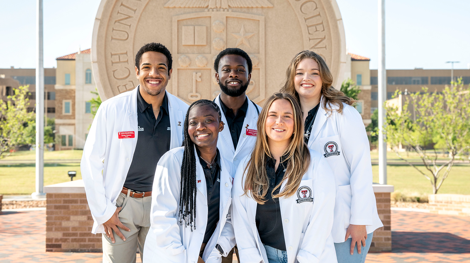Medicine students infront of TTUHSC stone seal on Lubbock Campus