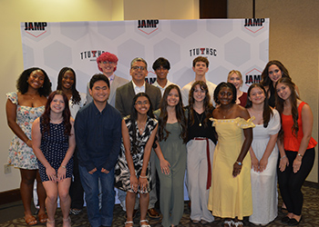 A group of TTUHSC Summer Enrichment students standing infront of a TTUHSC backdrop at a banquet smiling