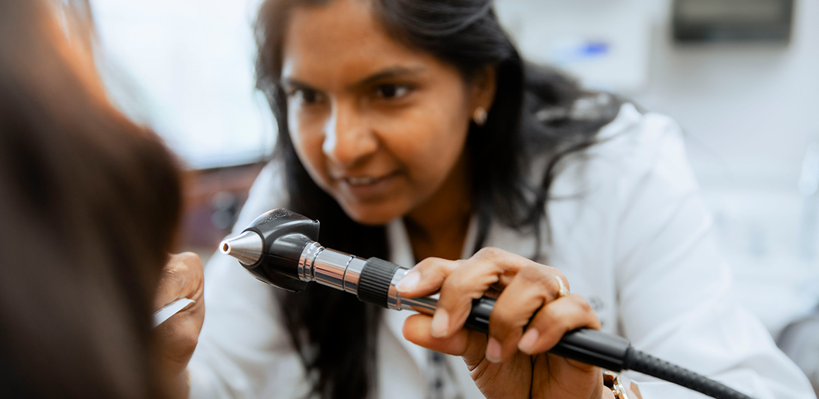 TTUHSC provider holding tool looking into patients throat