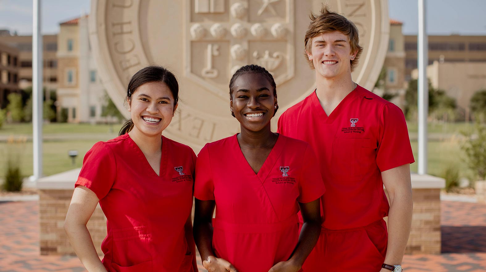 Nursing students infront of TTUHSC stone seal on Lubbock Campus